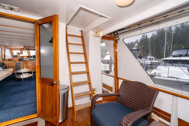 Slide: The Image of Interior of 1980 McQueen Motoryacht with wooden ladder, chair, and marina view. - 12