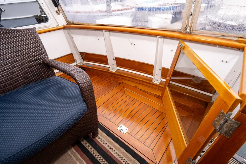Slide: The Image of 1980 McQueen Motoryacht interior with wooden flooring and wicker chair. - 16