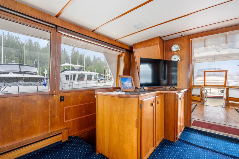 Slide: The Image of 1980 McQueen Motoryacht interior with wooden cabinetry, TV, and marina view through large windows. - 21
