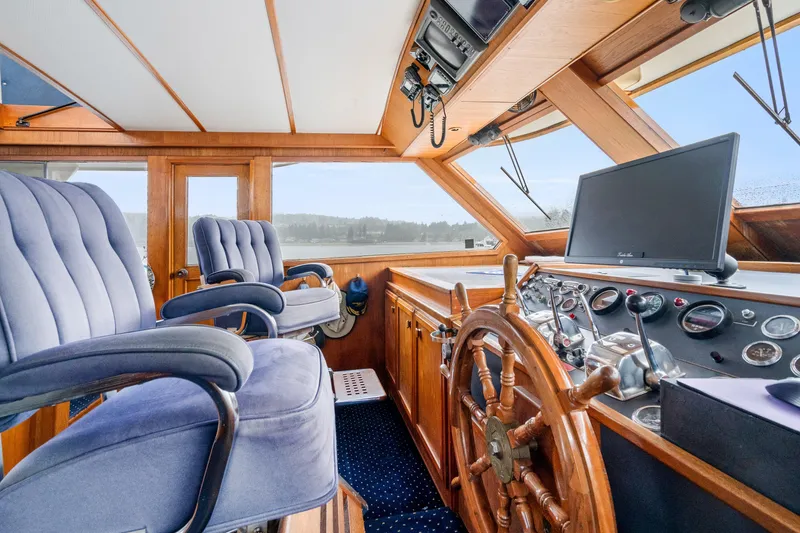Slide: The Image of 1980 McQueen Motoryacht helm with wooden wheel, blue captain chairs, and navigation equipment. - 25