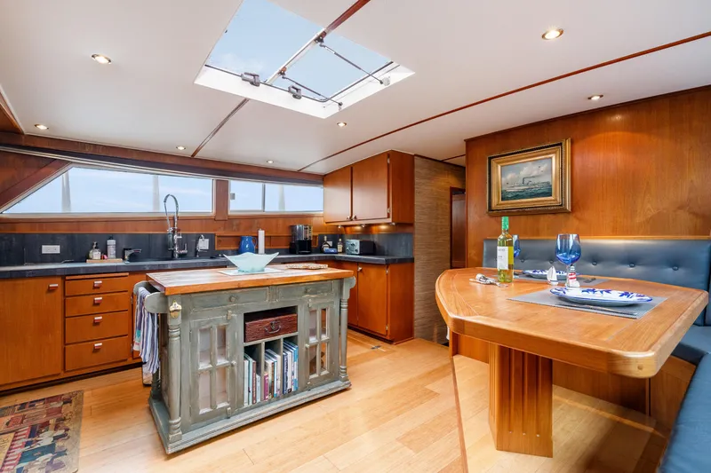 Slide: The Image of Luxurious 1980 McQueen Motoryacht kitchen with wood cabinetry, island, and dining area. - 29
