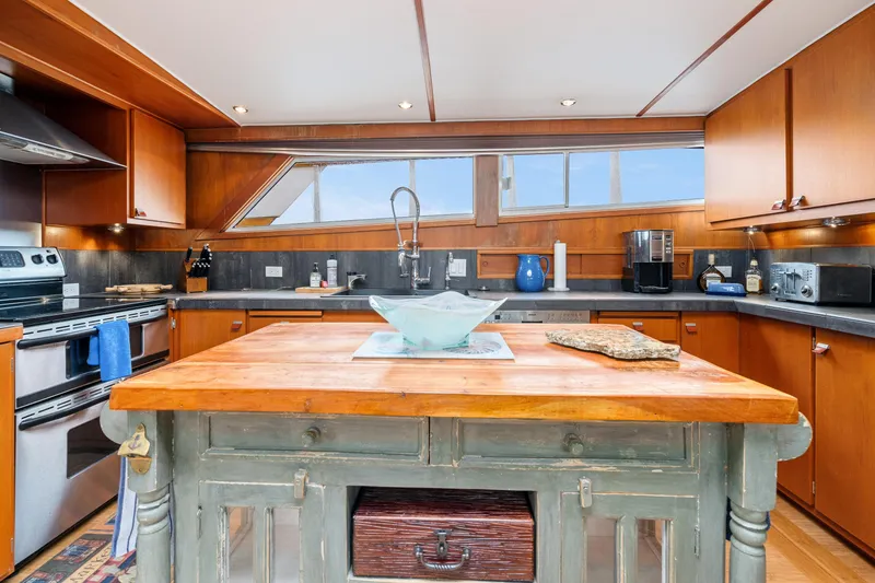 Slide: The Image of Luxurious kitchen interior of a 1980 McQueen Motoryacht with wooden cabinetry and modern appliances. - 30
