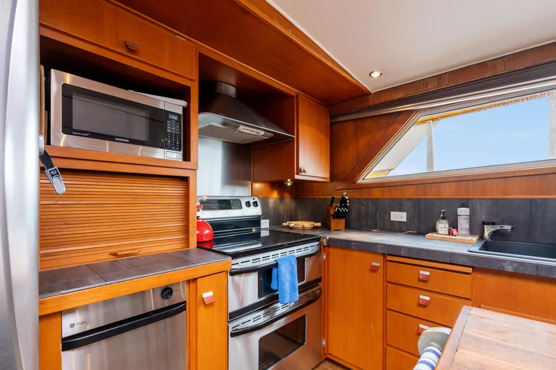Slide: The Image of 1980 McQueen Motoryacht kitchen with modern appliances, wooden cabinetry, and a large window. - 33