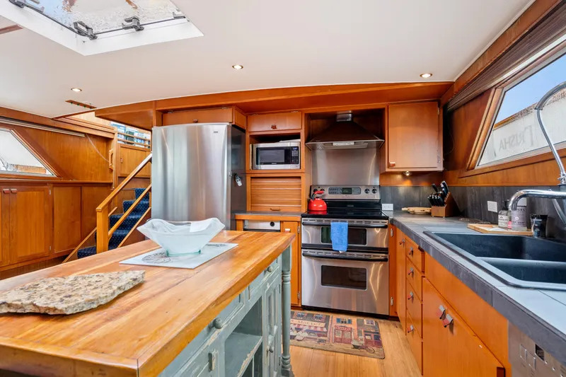 Slide: The Image of 1980 McQueen Motoryacht kitchen with wooden cabinetry, stainless steel appliances, and skylight. - 35