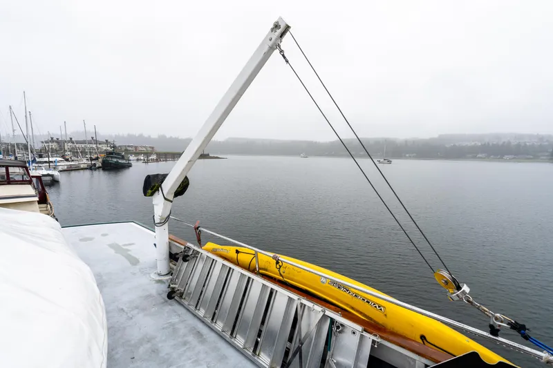 Slide: The Image of 1980 McQueen Motoryacht deck with crane and yellow kayak, overlooking a foggy marina. - 47