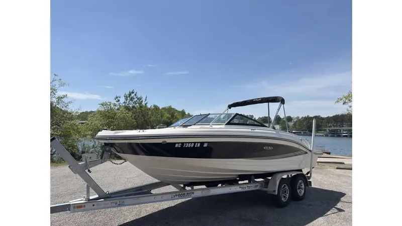 Slide: The Image of 2016 Sea Ray SPX 210 boat on trailer by a lake, under clear blue sky. - 1