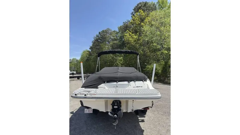 Slide: The Image of 2016 Sea Ray SPX 210 boat, rear view, parked outdoors with trees in background. - 14