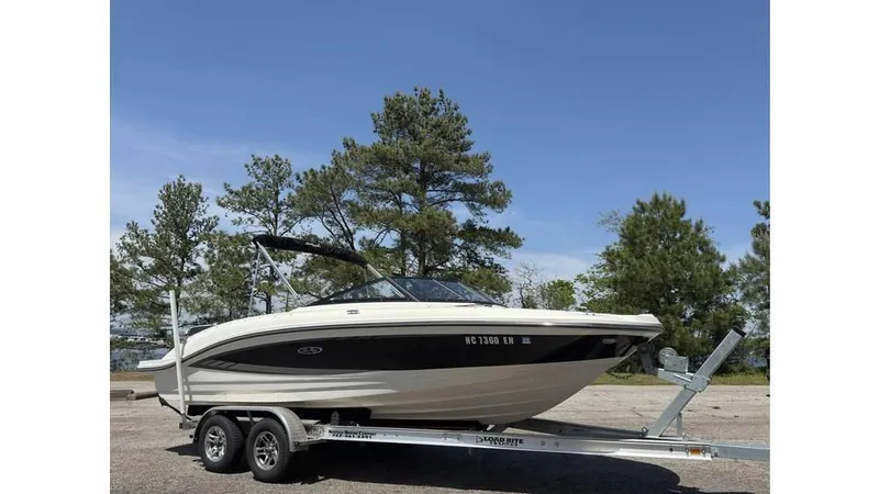 Slide: The Image of 2016 Sea Ray SPX 210 boat on trailer, parked outdoors with trees in background. - 2