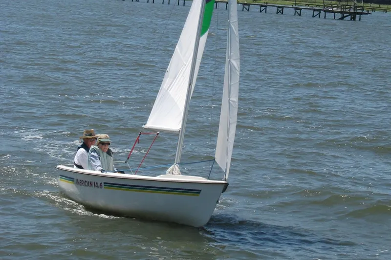 Slide: The Image of Sailboat American 14.6 on water, two people aboard, sunny day, 2025 model. - 4