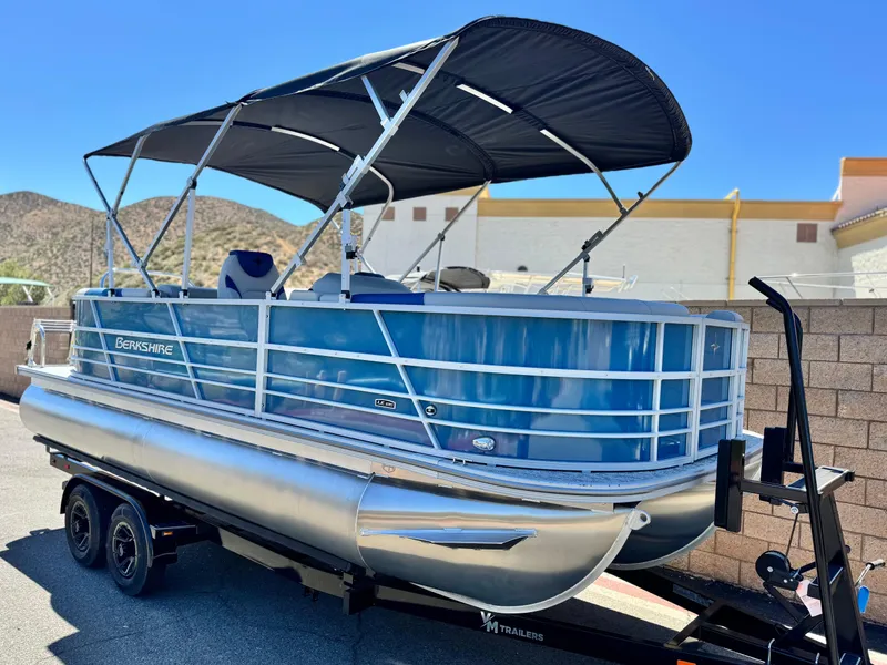 Slide: The Image of 2025 Berkshire 22RFX LE pontoon boat on trailer, featuring blue exterior and black canopy. - 1