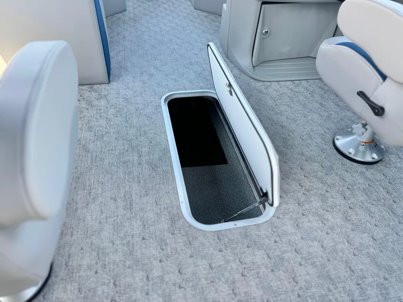 Slide: The Image of 2025 Berkshire 22RFX LE boat interior with open storage compartment on carpeted floor. - 17