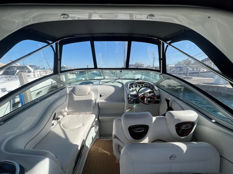 Slide: The Image of 2008 Crownline 270 CR boat interior with white seating and steering wheel, docked at marina. - 16