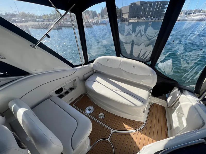 Slide: The Image of 2008 Crownline 270 CR boat interior with white seating and wood flooring, dockside view. - 7