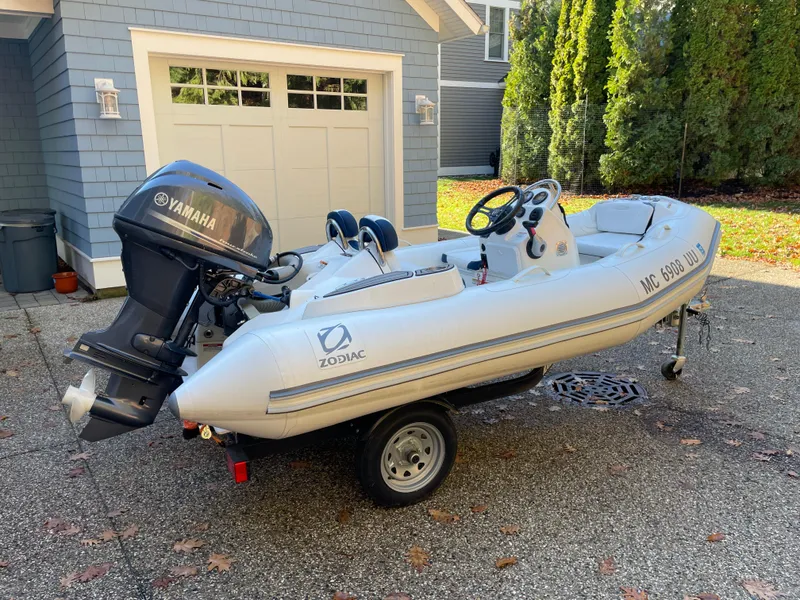 Slide: The Image of 2022 Zodiac Yachtline 360 inflatable boat with Yamaha motor on a trailer in a driveway. - 2