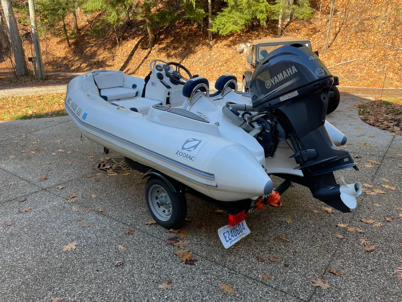 Slide: The Image of 2022 Zodiac Yachtline 360 inflatable boat with Yamaha motor on a trailer, parked outdoors. - 3