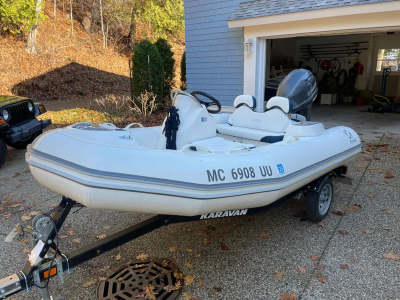Slide: The Image of 2022 Zodiac Yachtline 360 inflatable boat on trailer, parked outside a garage. - 7