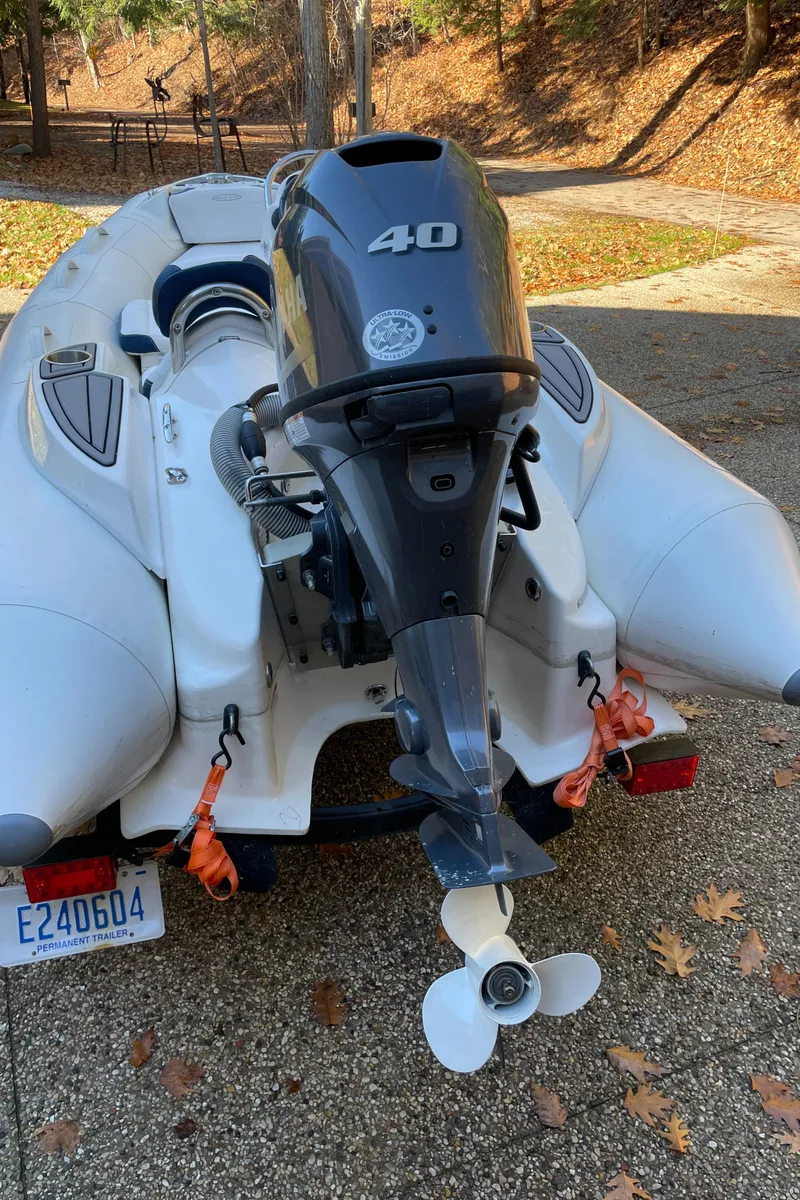Slide: The Image of 2022 Zodiac Yachtline 360 inflatable boat with a 40 HP outboard motor, parked on a driveway. - 9