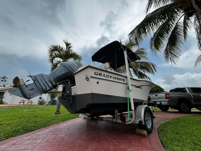 Slide: The Image of 2013 Grady-White Fisherman 180 boat on trailer, parked near palm trees and a truck. - 11
