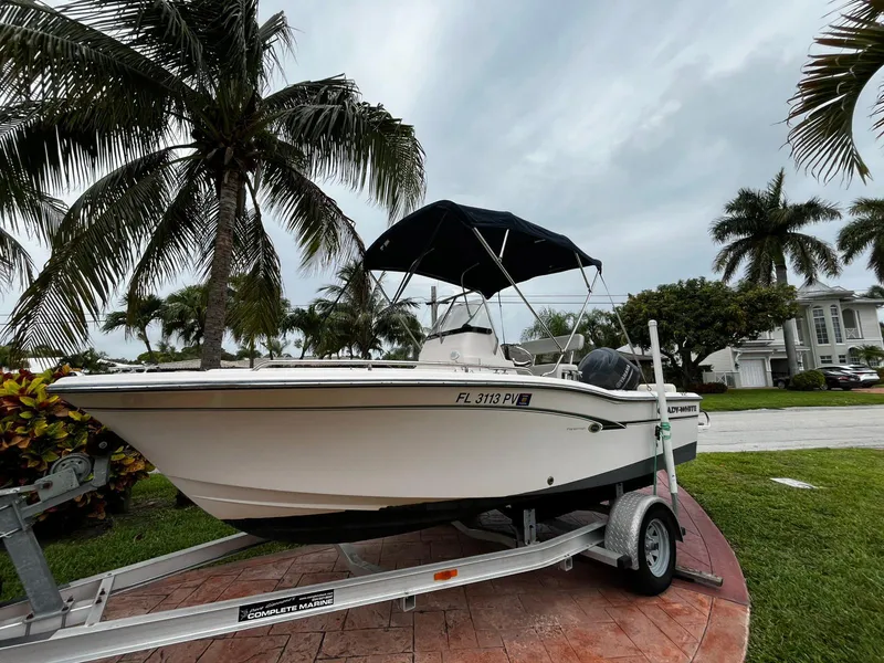 Slide: The Image of 2013 Grady-White Fisherman 180 boat on trailer, surrounded by palm trees. - 2