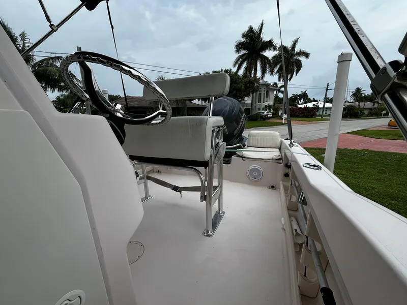 Slide: The Image of 2013 Grady-White Fisherman 180 boat interior with steering wheel and seating, parked near palm trees. - 36