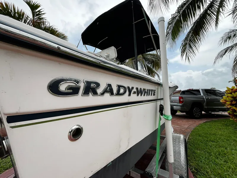 Slide: The Image of 2013 Grady-White Fisherman 180 boat on trailer, surrounded by palm trees and parked truck. - 4