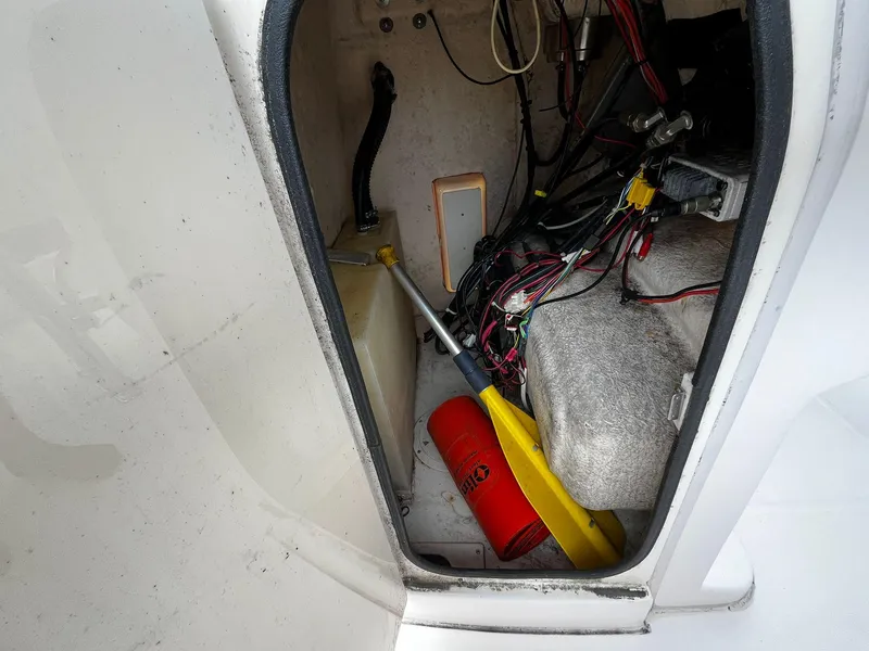 Slide: The Image of 2013 Grady-White Fisherman 180 storage compartment with wiring, paddle, and safety equipment. - 44