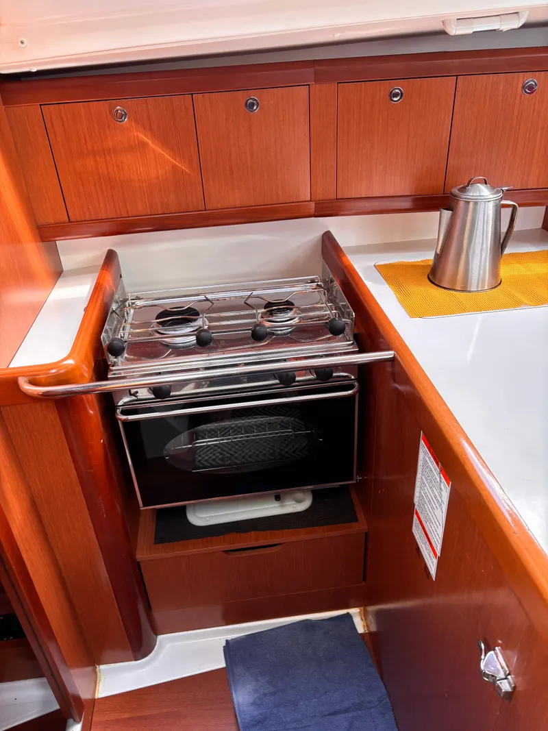 Slide: The Image of 2009 Beneteau Oceanis 34 yacht kitchen with stove, oven, and wooden cabinetry. - 9
