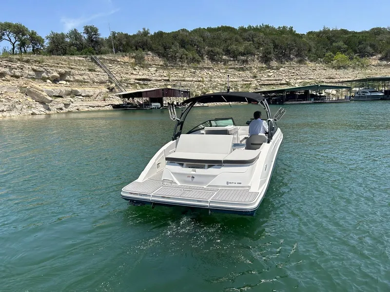 Slide: The Image of 2020 Sea Ray SPX 230 boat cruising on a serene lake near rocky shoreline. - 12