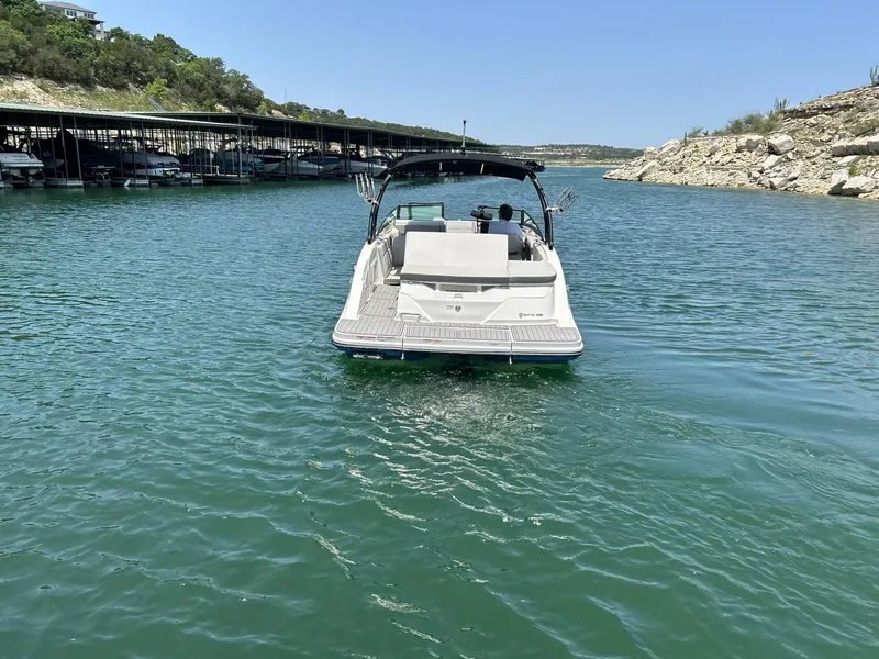 Slide: The Image of 2020 Sea Ray SPX 230 boat on a serene lake near a marina. - 13