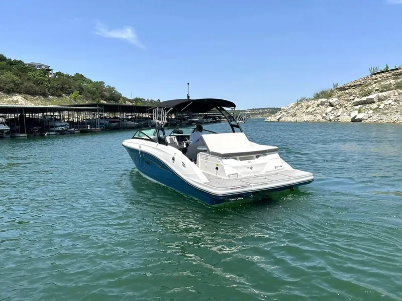 Slide: The Image of 2020 Sea Ray SPX 230 boat cruising on a sunny lake with rocky shoreline. - 14