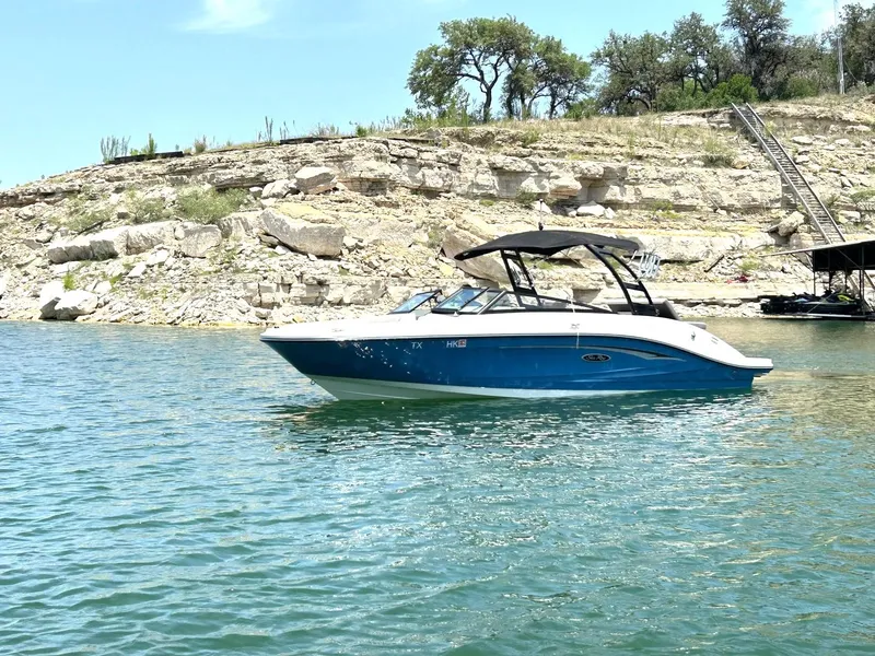 Slide: The Image of 2020 Sea Ray SPX 230 boat on a serene lake with rocky shoreline. - 17