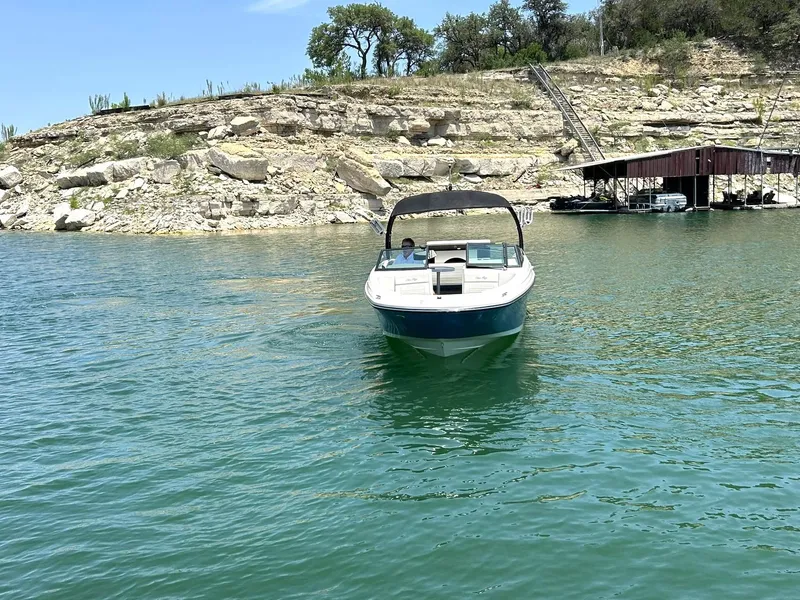 Slide: The Image of 2020 Sea Ray SPX 230 boat on a serene lake with rocky shoreline. - 18