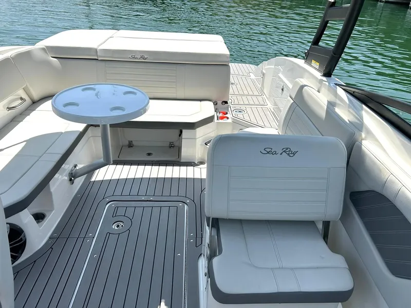 Slide: The Image of 2020 Sea Ray SPX 230 boat interior with seating and table, on calm water. - 35