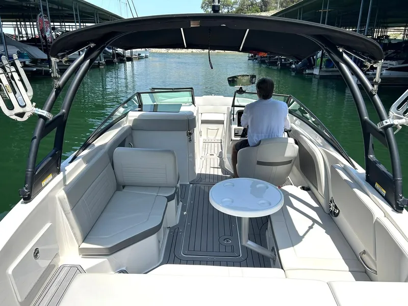 Slide: The Image of 2020 Sea Ray SPX 230 boat interior with seating and table, docked in a marina. - 4