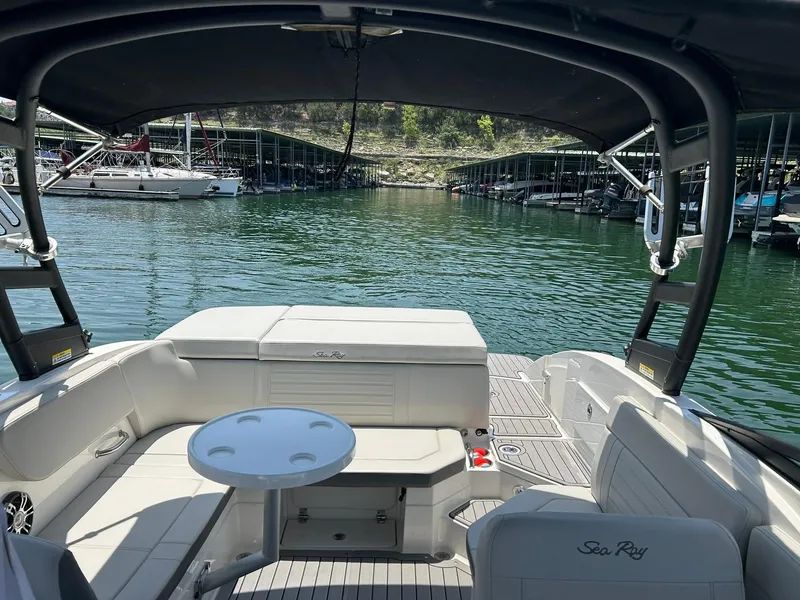 Slide: The Image of 2020 Sea Ray SPX 230 boat interior with seating and table, docked in a marina. - 5