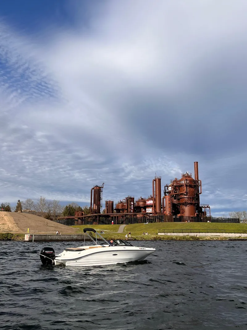 Slide: The Image of 2021 Sea Ray SPX 210 OB boat on water near industrial structure under cloudy sky. - 12