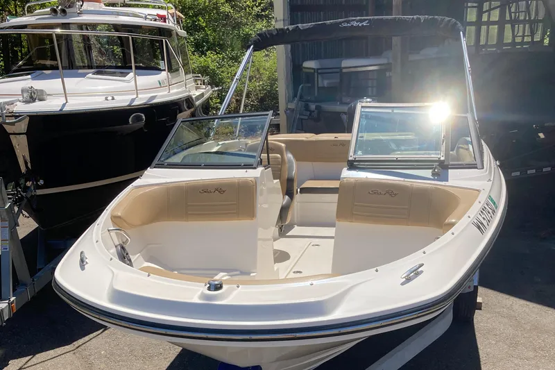 Slide: The Image of 2021 Sea Ray SPX 210 OB boat with open bow and dual windshields, parked outdoors. - 8