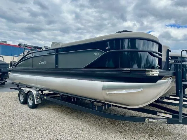The Image of 2025 Barletta C24M pontoon boat on trailer, parked outdoors under cloudy sky. - 1