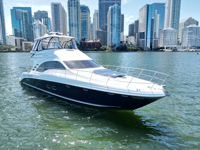 The Image of 2005 Sea Ray 58 Sedan Bridge yacht on water with city skyline backdrop. - 0