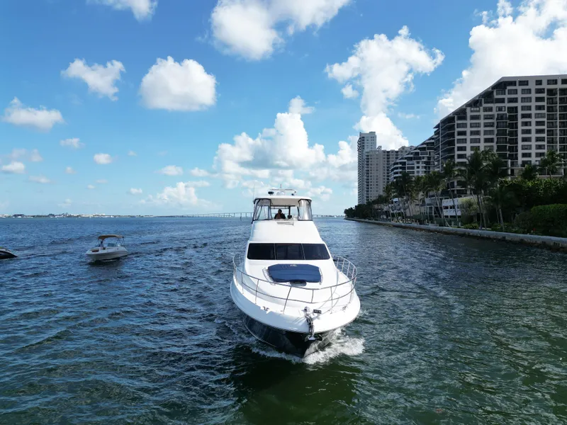 Slide: The Image of 2005 Sea Ray 58 Sedan Bridge yacht cruising near coastal buildings under blue sky. - 12