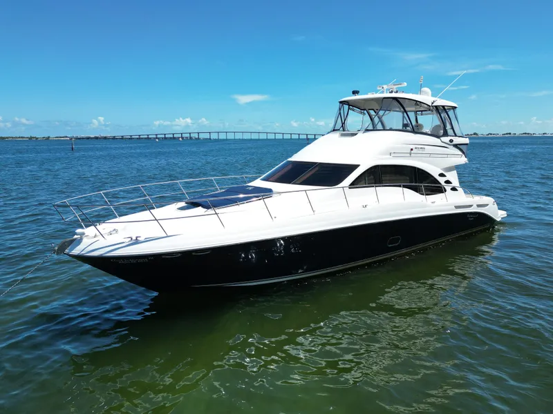 Slide: The Image of 2005 Sea Ray 58 Sedan Bridge yacht on calm water under clear blue sky. - 2
