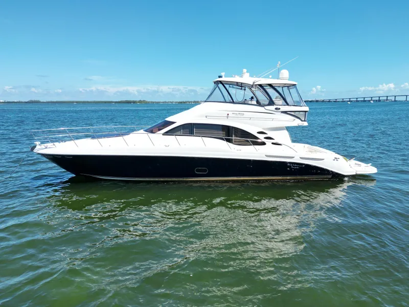 Slide: The Image of 2005 Sea Ray 58 Sedan Bridge yacht on calm water under clear blue sky. - 3
