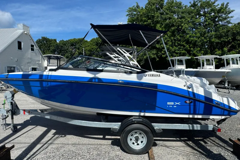 Slide: The Image of 2025 Yamaha Boats SX195 in blue, parked on a trailer, with a black canopy. - 17