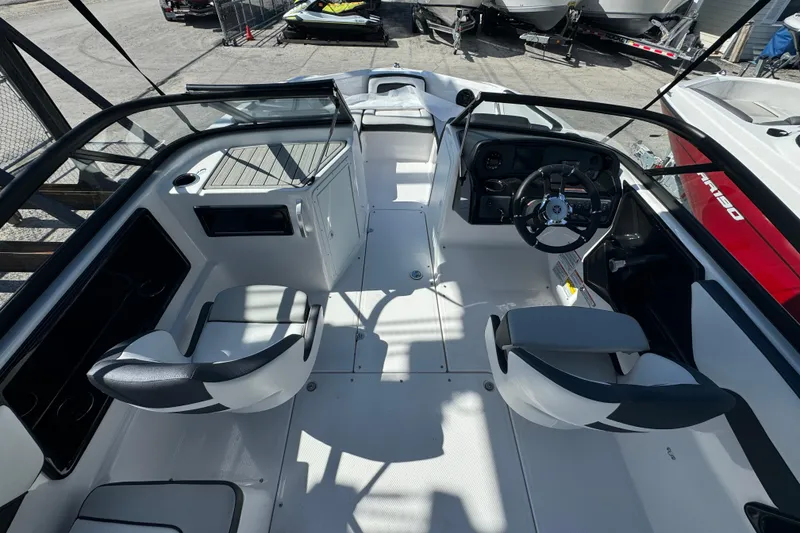 Slide: The Image of 2025 Yamaha Boats SX195 interior with steering wheel and seating, docked outdoors. - 21