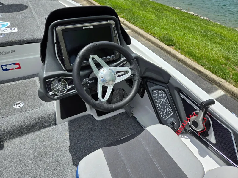 Slide: The Image of 2015 Skeeter FX 20 boat cockpit with steering wheel and control panel by the water. - 12