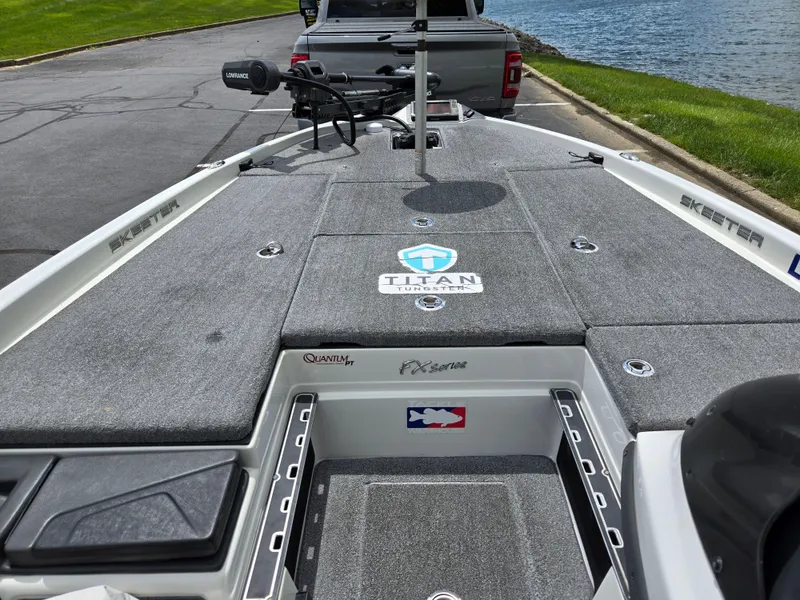 Slide: The Image of 2015 Skeeter FX 20 boat deck with storage compartments and fishing gear, near a lake. - 13