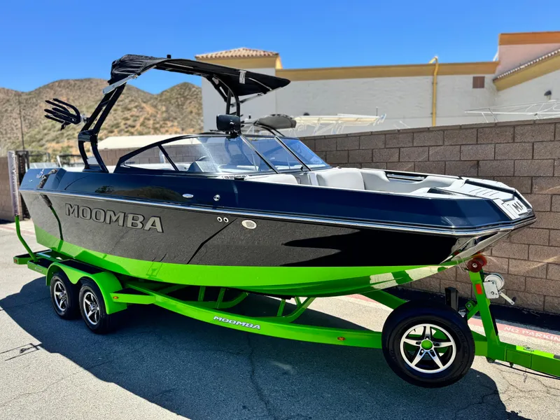Slide: The Image of 2020 Moomba Max boat on a vibrant green trailer, parked outdoors. - 1