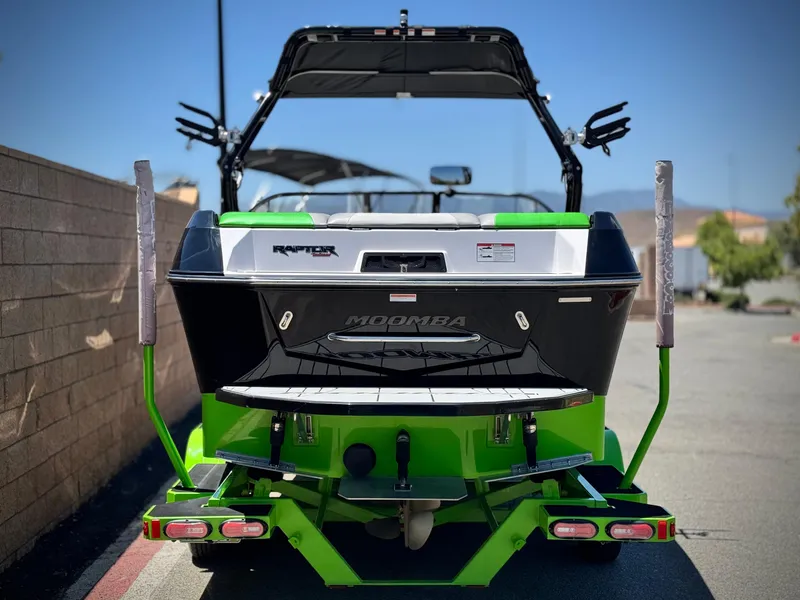 Slide: The Image of 2020 Moomba Max boat, rear view, vibrant green and black design, parked outdoors. - 4