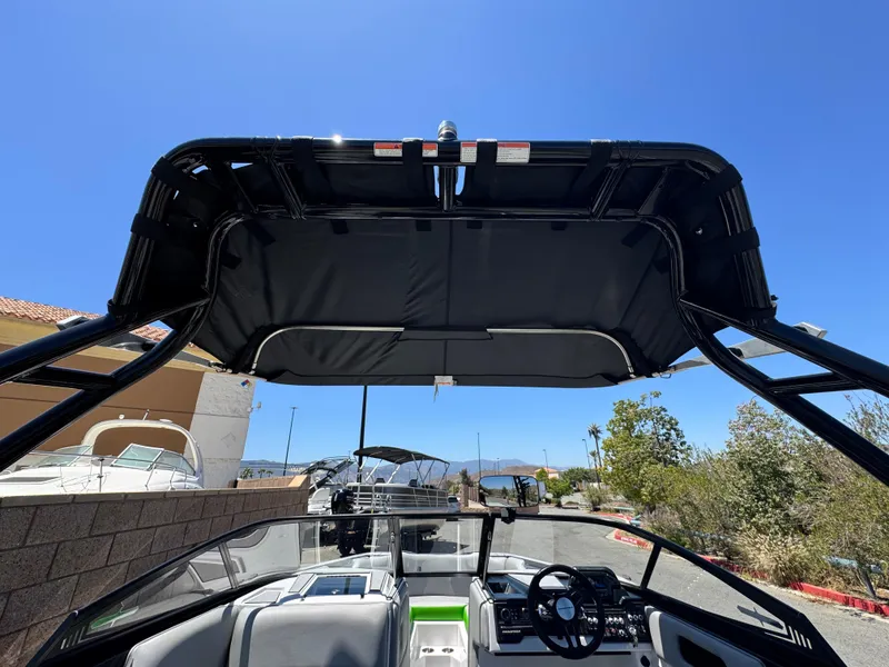 Slide: The Image of 2020 Moomba Max boat interior with canopy, steering wheel, and seating under clear blue sky. - 8