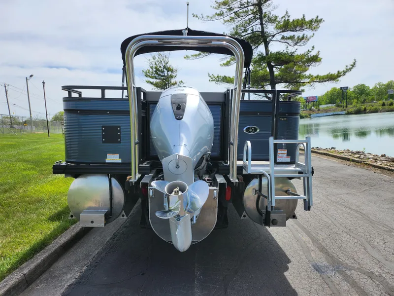 Slide: The Image of 2023 Qwest 8522 Pro Family Fish pontoon boat, rear view with motor, near a lake. - 2